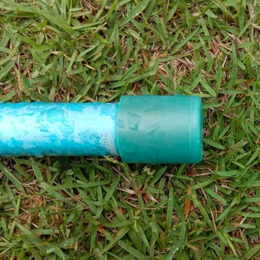 Teal UPVC pipe end cap plug fitting attached to a short green pipe section
