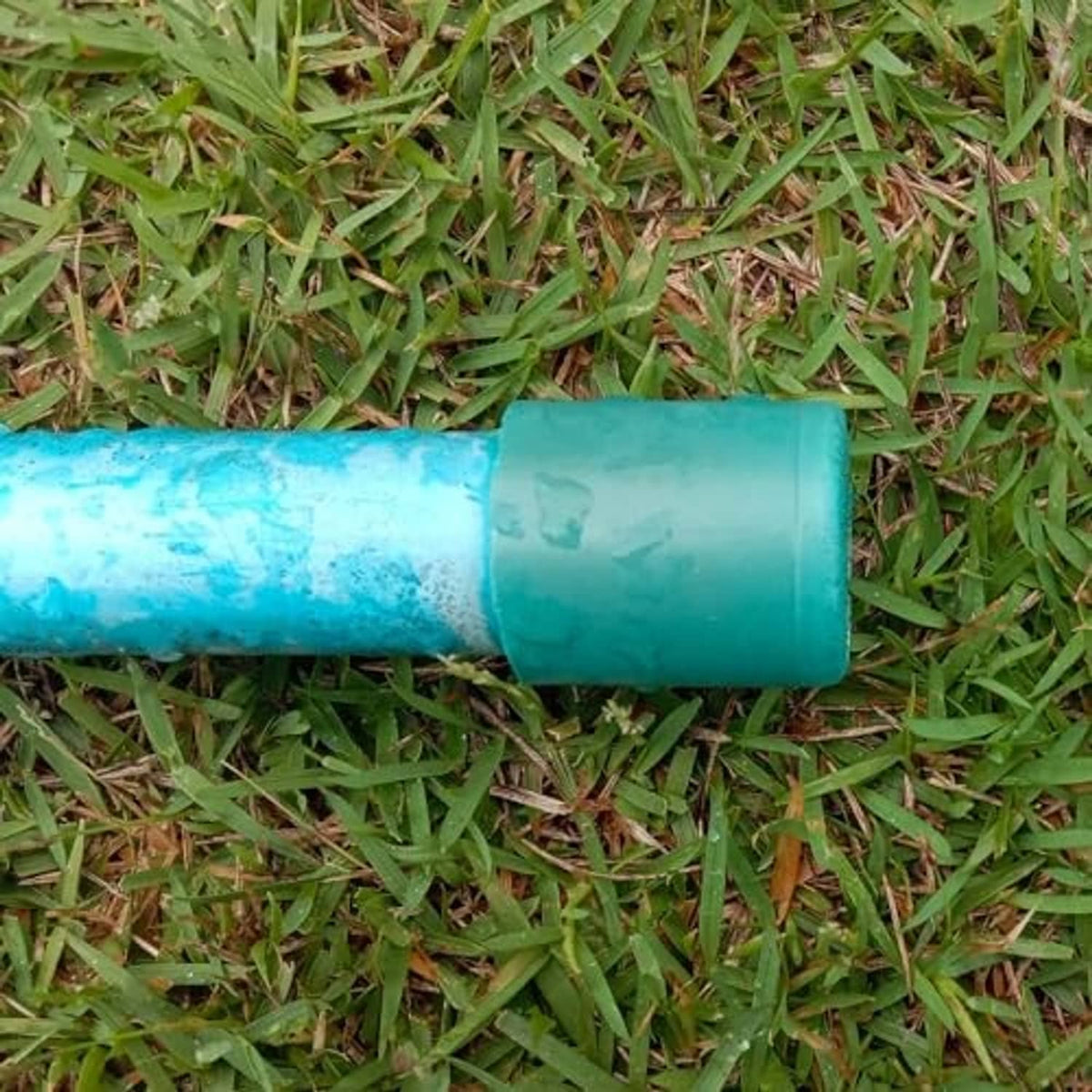 Teal UPVC pipe end cap plug fitting attached to a short green pipe section