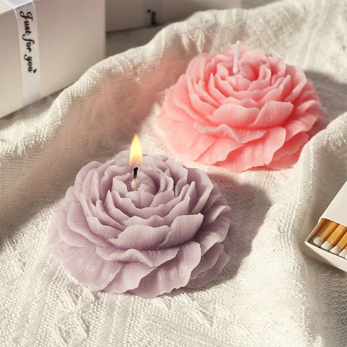 Pink and lavender peony flower candles with a lit wick