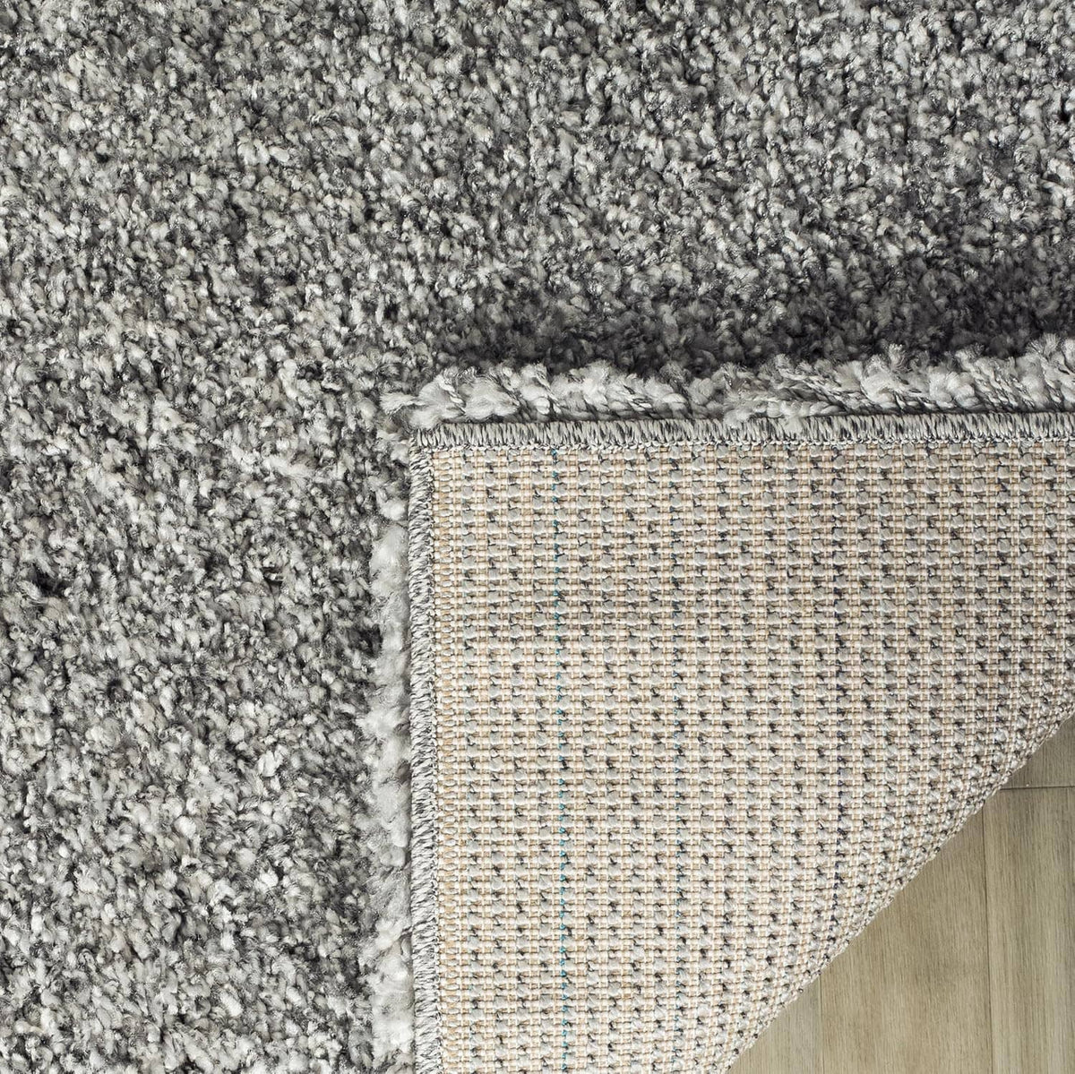 Silver shag rug corner with stitched border and textured backing