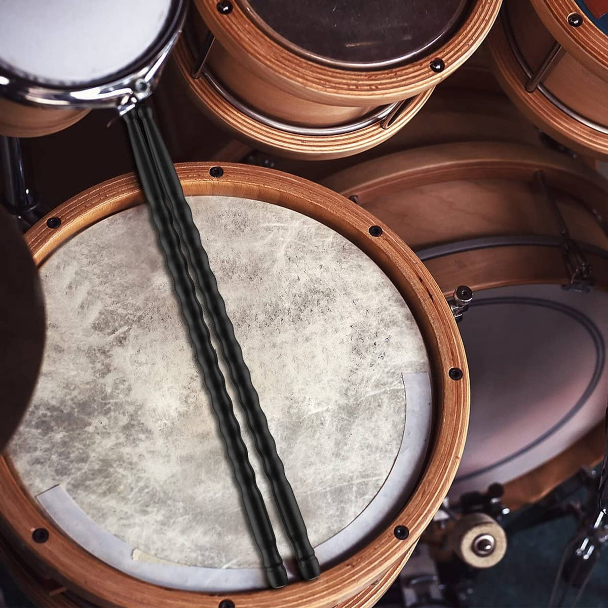 Black carbon fiber drumsticks striking a snare drum head