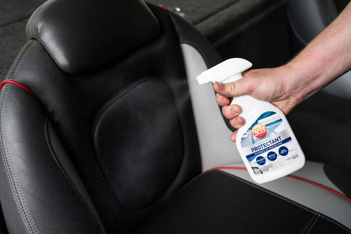 Hand spraying aerospace protectant onto black vehicle seat
