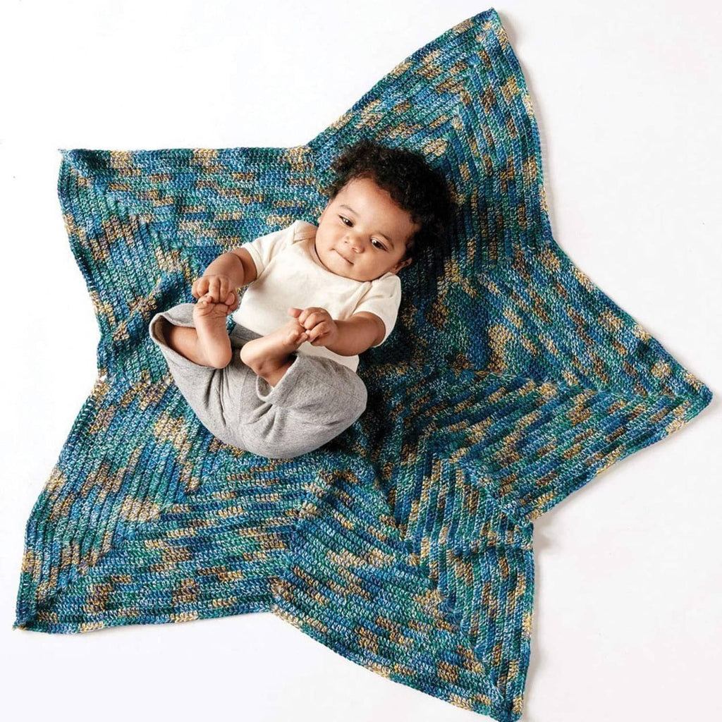 Teal and tan knit star-shaped baby blanket with infant lying on it