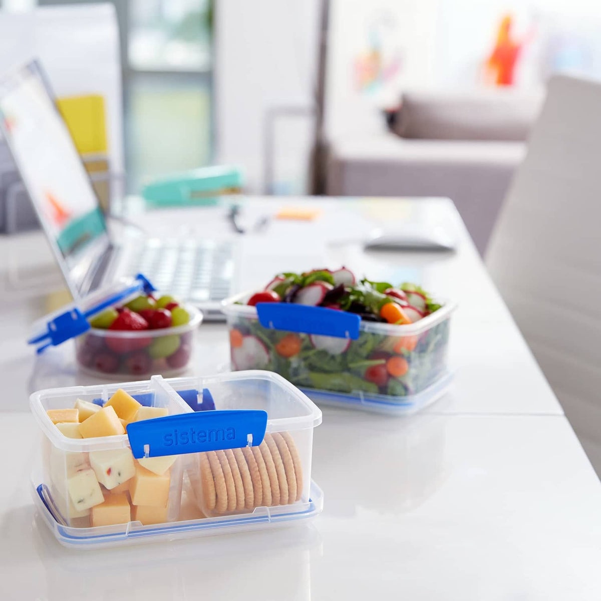 Rectangular food storage containers with blue snap lids on kitchen table