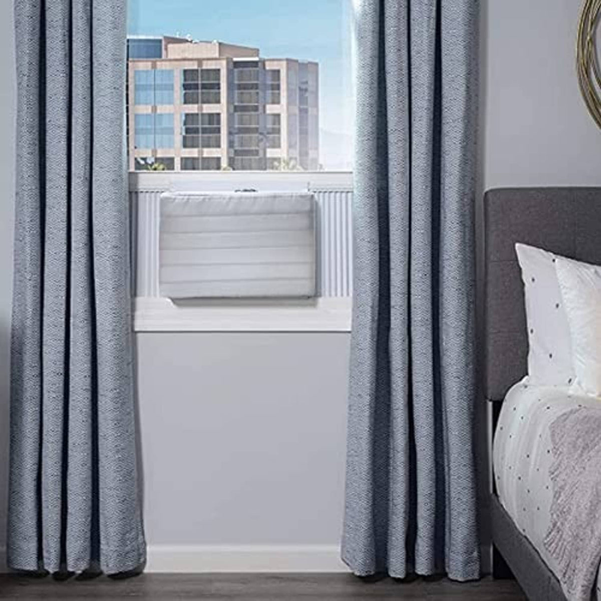 Window AC cover installed in window opening, padded white behind curtains