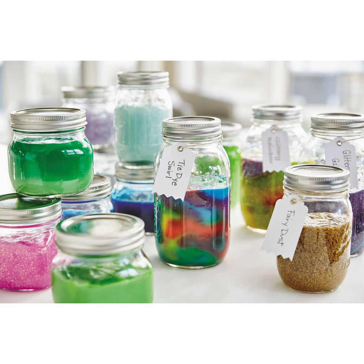 Multiple small jars of colored slime and bottles with caps on a table