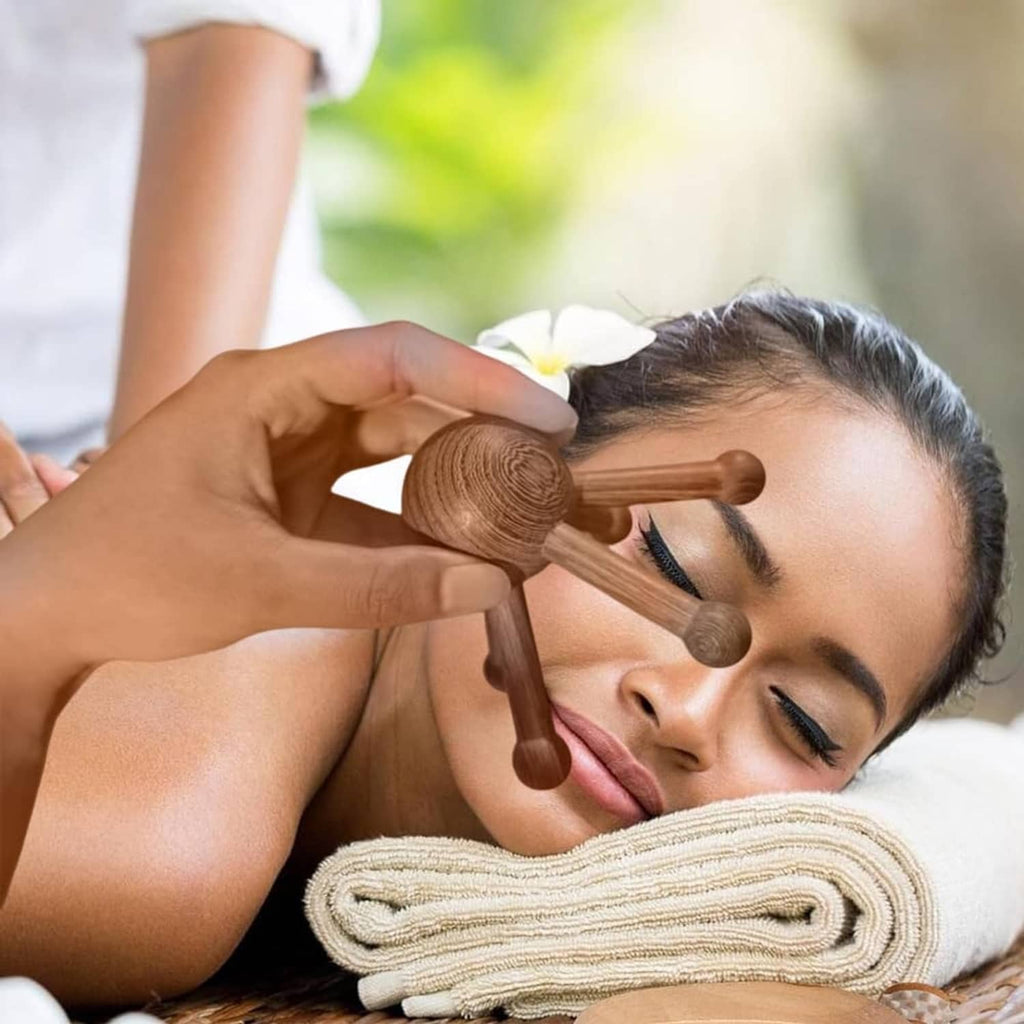 Brown 5-legged wooden trigger point massager used on forehead and temple while lying down.