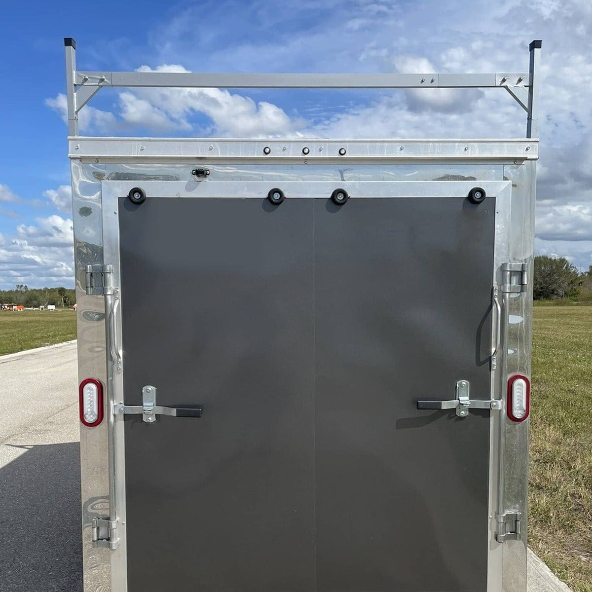 Front view of enclosed trailer with roof mount ladder rack bracket, white posts and top bar