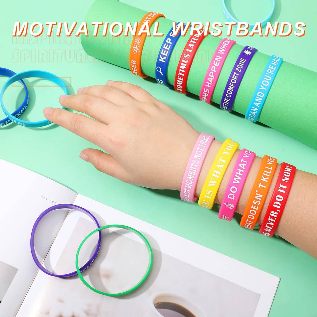 Hand arranging multicolor motivational silicone wristbands on a light card