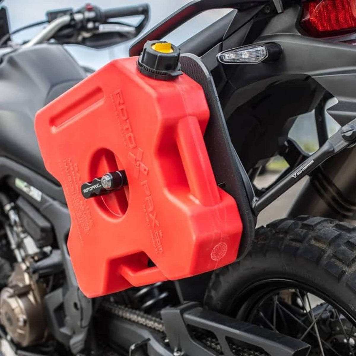 Red gasoline canister with yellow cap, positioned on motorcycle fuel area