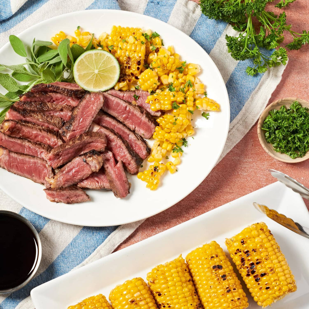 Steak with oyster-sauce glaze and grilled corn on a white plate with lime