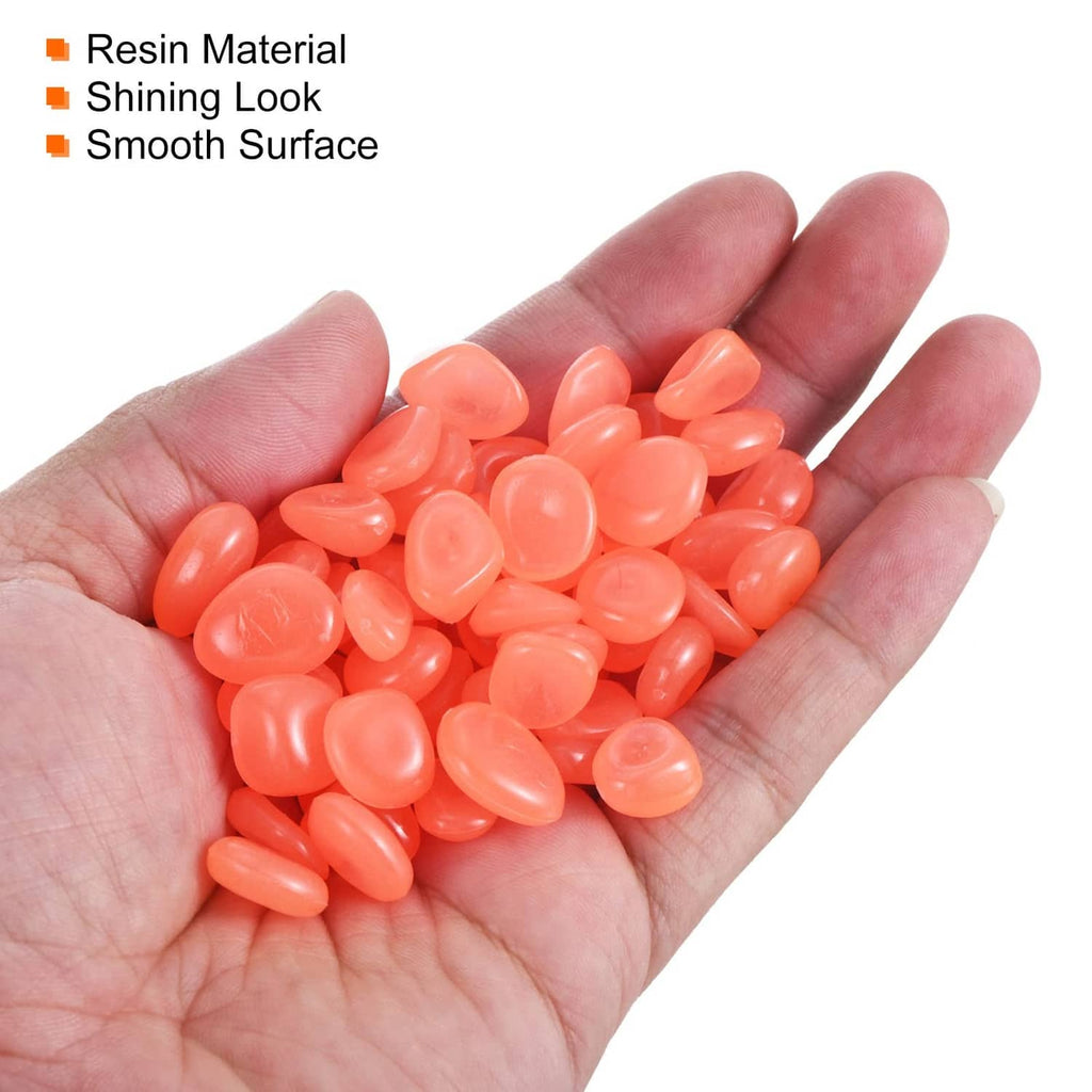 Orange glow rock pebbles in hand, smooth oval resin stones