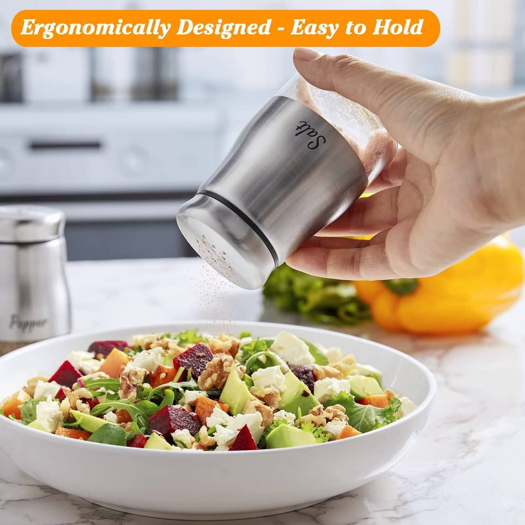 Stainless steel salt and pepper shaker held in hand over a bowl of food.