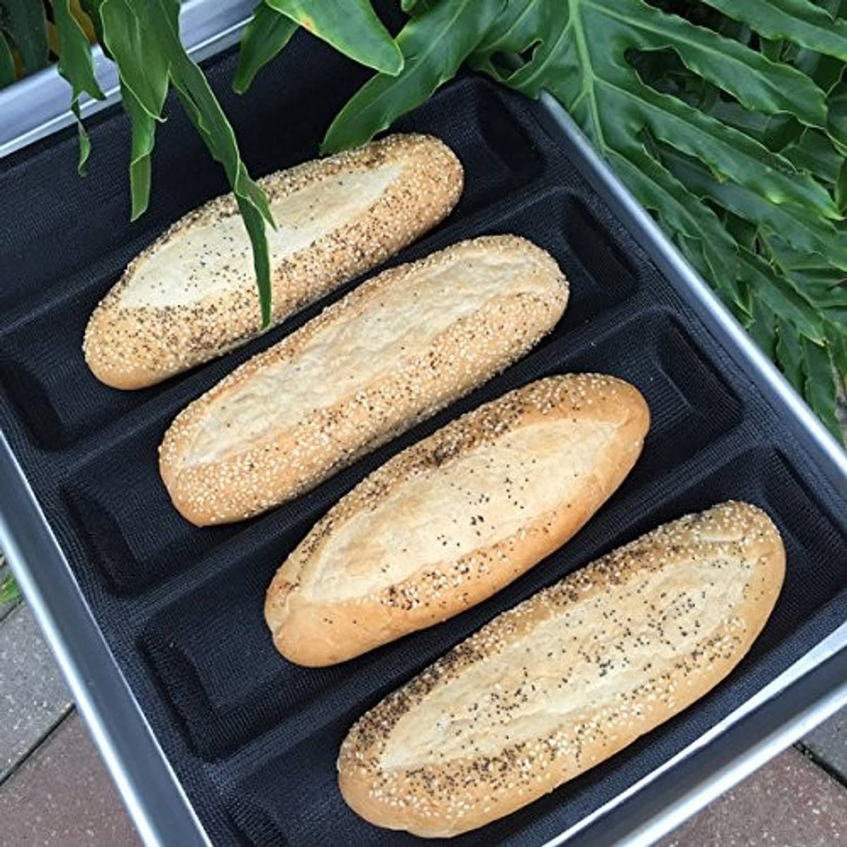 Black 5-cavity hot dog bread mold tray with four uncooked dough logs