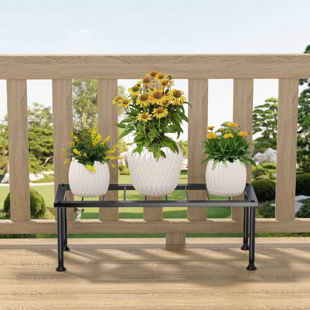 Black metal long rectangular plant stand with three potted flowers on slatted shelf
