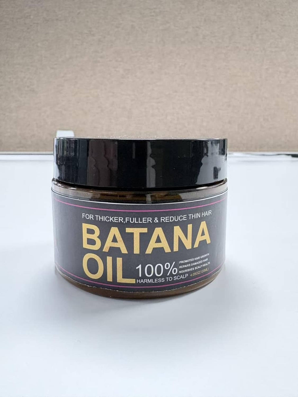 Batana oil 100% hair jar with black lid and gold text, amber-brown oil