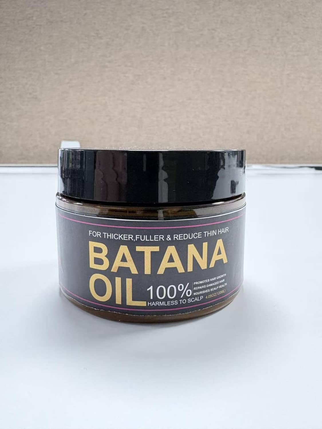 Batana oil 100% hair jar with black lid and gold text, amber-brown oil