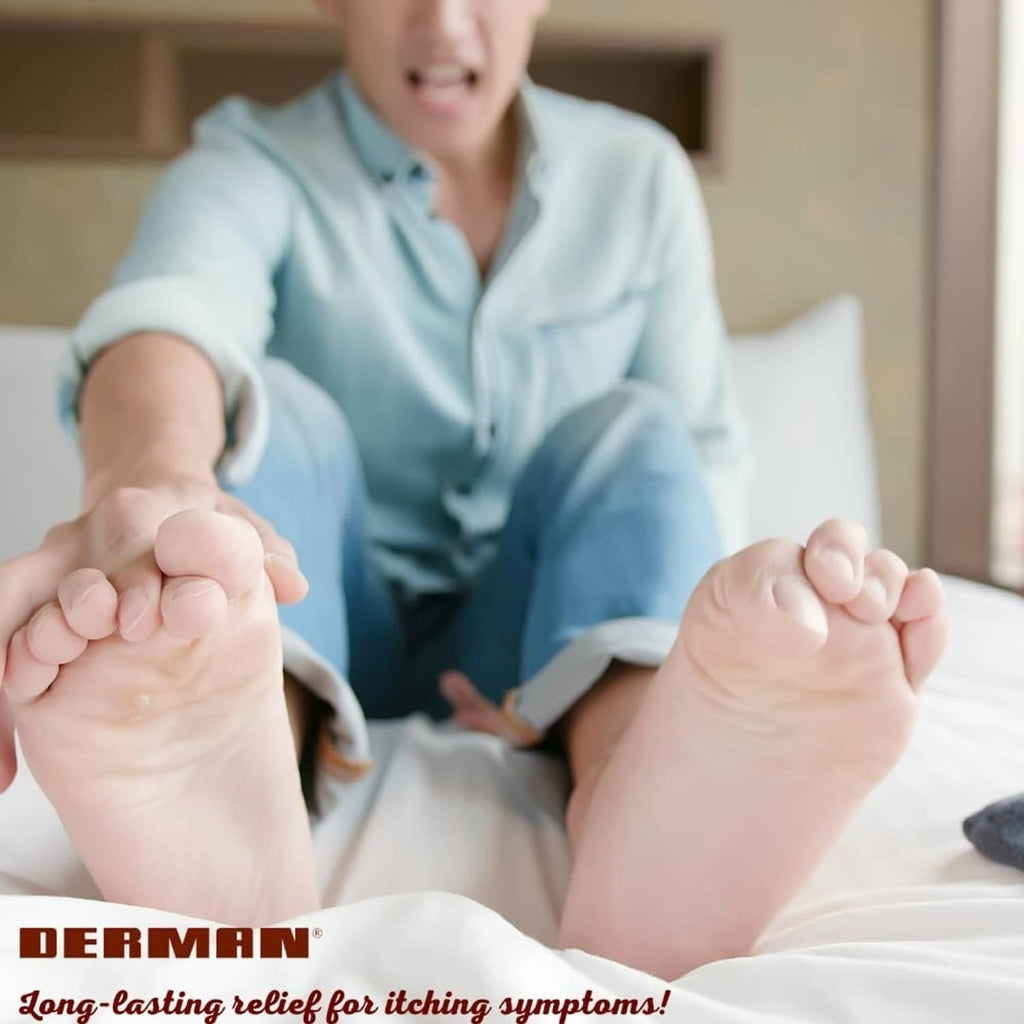 Person applying Derman antifungal cream to feet while relaxing on a bed.