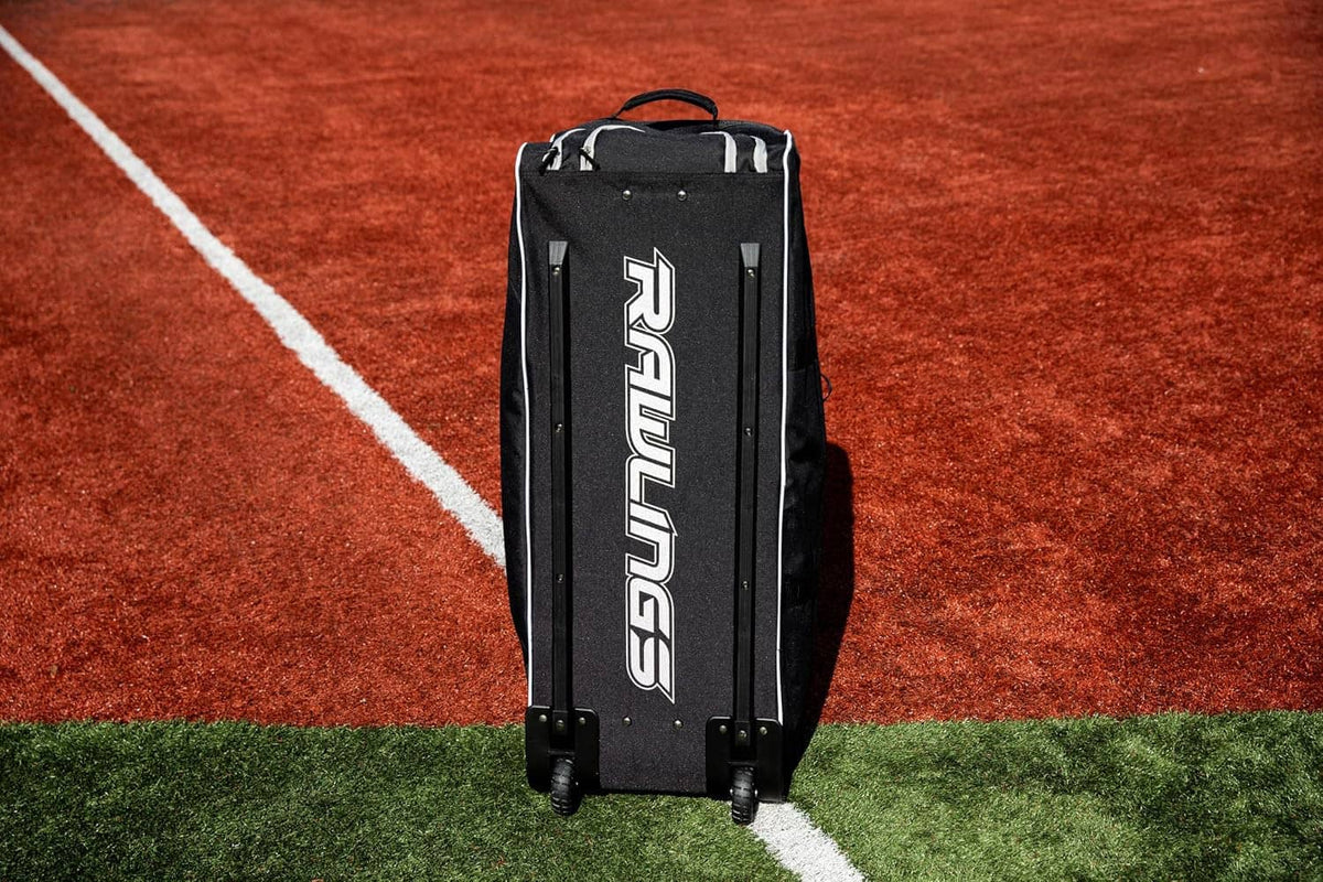 Rear view of black wheeled catcher’s bag with vertical Rawlings logo and wheels