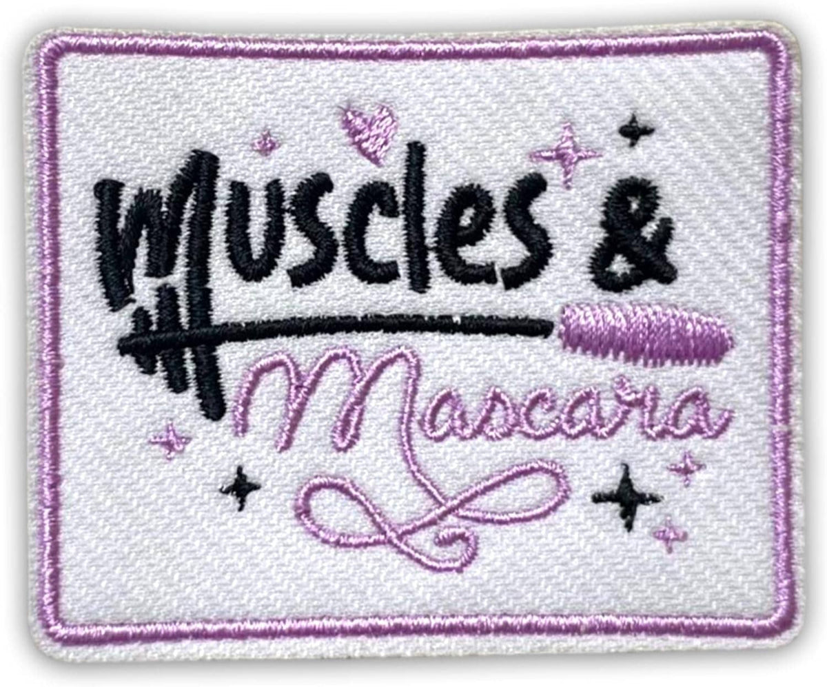 Iron-on fabric patch showing embroidered 'Muscles & Mascara' lettering with purple trim.