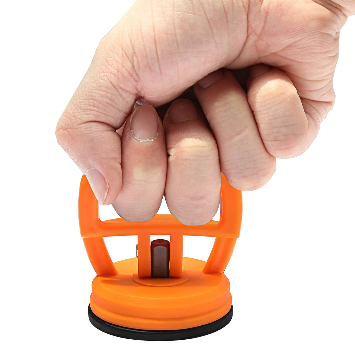 Orange suction cup dent puller tool held by hand above black rubber base
