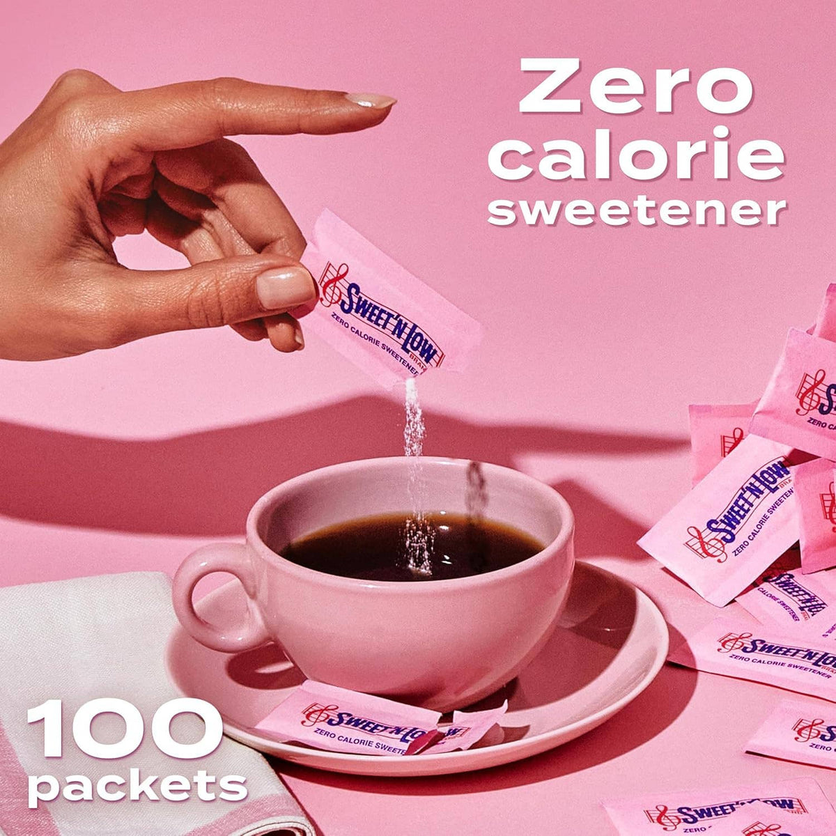 Hand pouring Sweet 'n Low zero-calorie sweetener packet into a cup of dark coffee