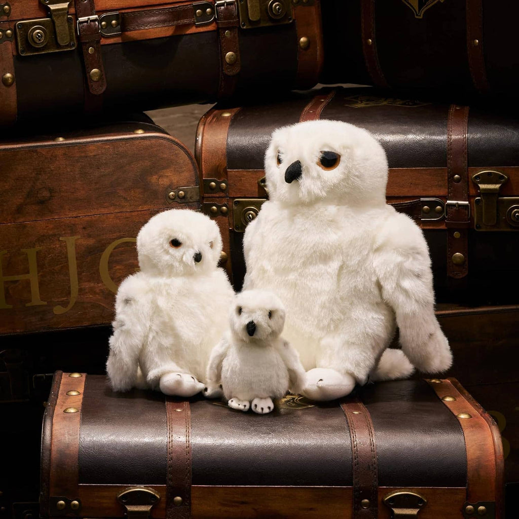 Family of plush snowy owls in white fur: one large and two small owls