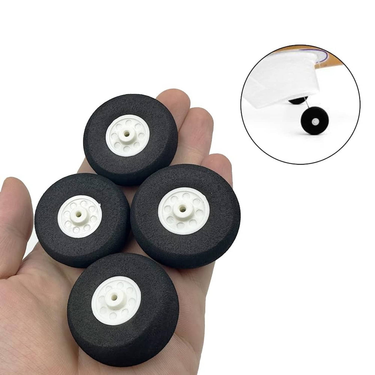 Black foam RC airplane wheels with white hubs held in hand, close-up inset