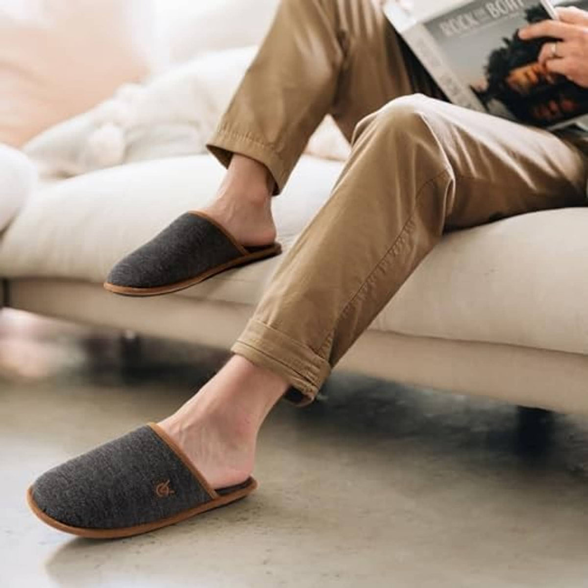 Dark gray knitted slip-on slippers with brown trim and blue plaid lining on feet