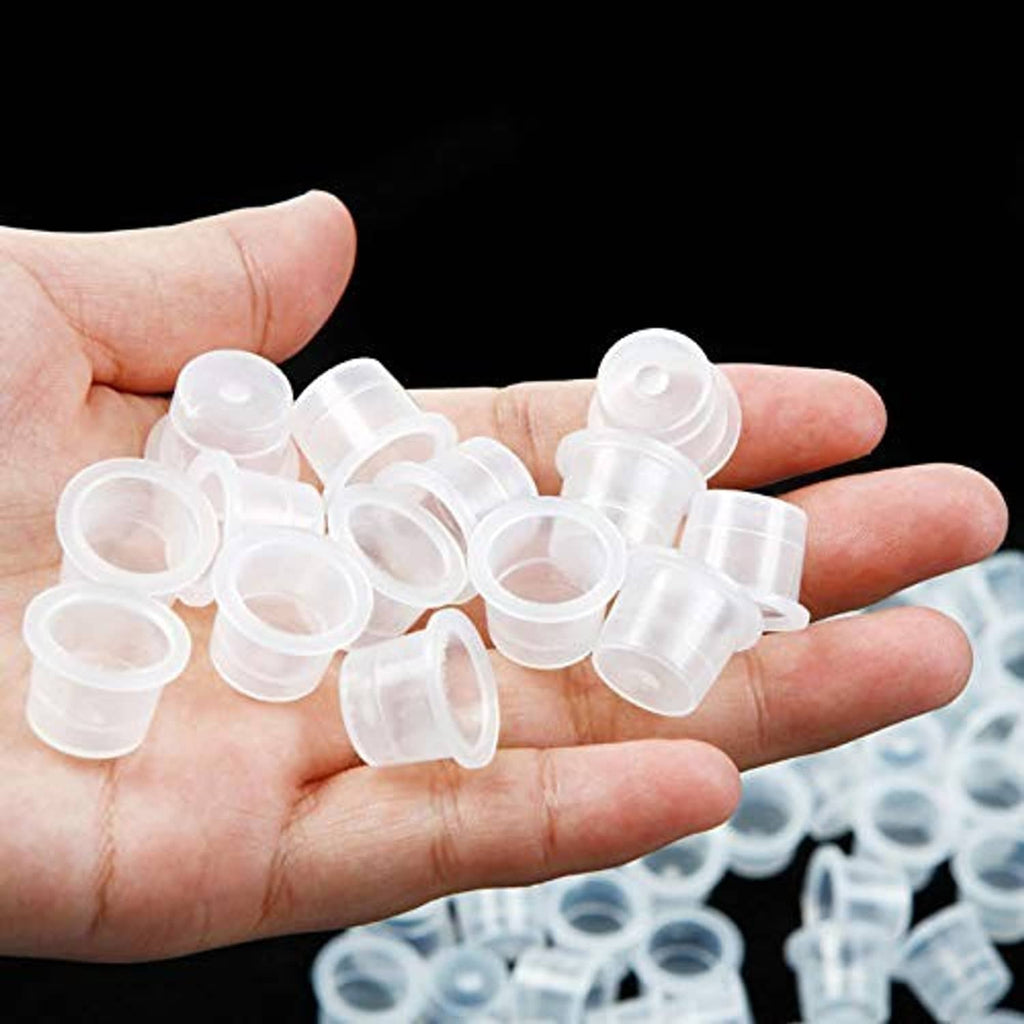 Disposable clear tattoo ink caps in hand, small transparent mini cup lids