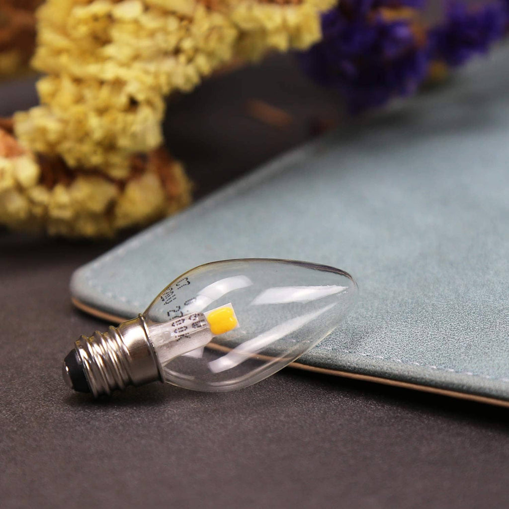 Close-up of clear teardrop LED bulb with yellow LED chip and metal screw base