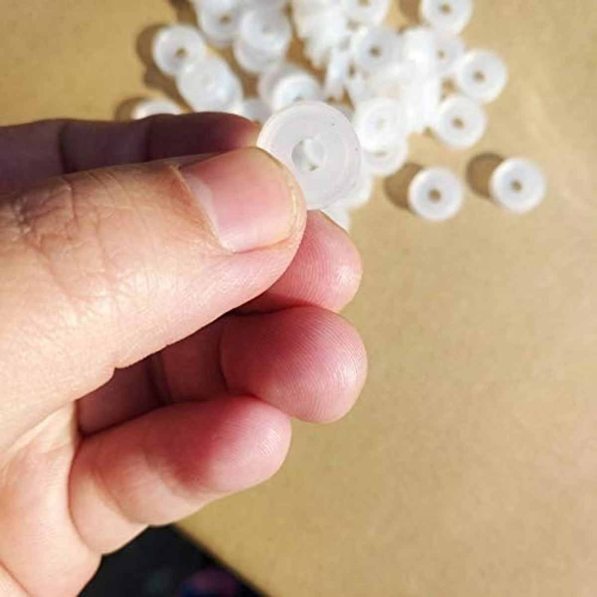 Single white plastic sealing ring shown between fingers