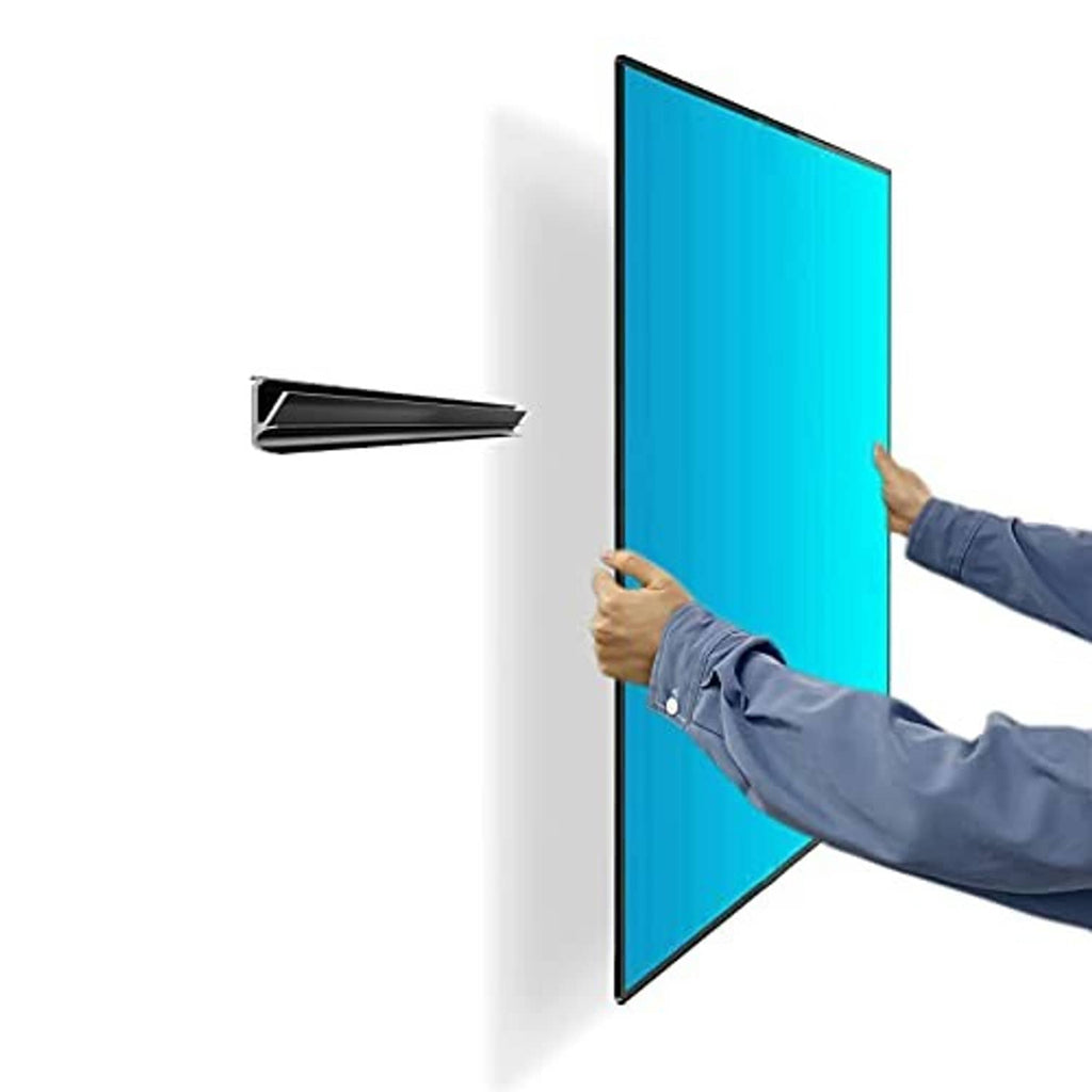 Slim black no-stud TV wall mount bar mounting a flat TV with hands on drywall
