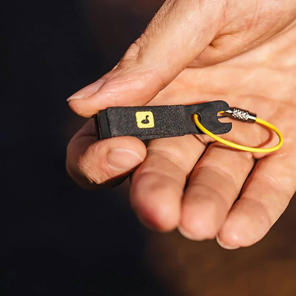 Black nippers handle with yellow cord and metal cutting jaws, held in hand