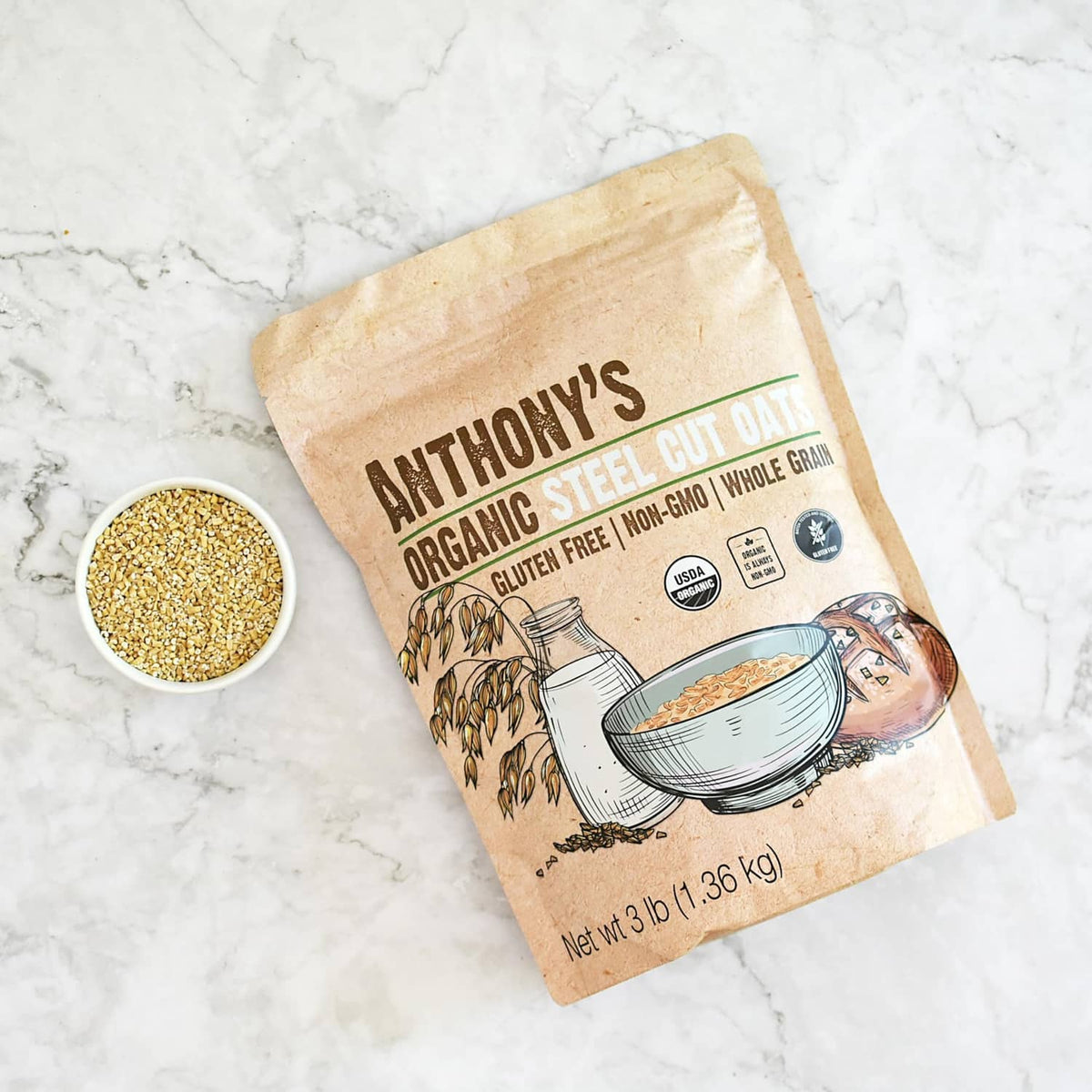 Anthony's organic steel cut oats pouch with a bowl of steel cut oats on a marble surface.