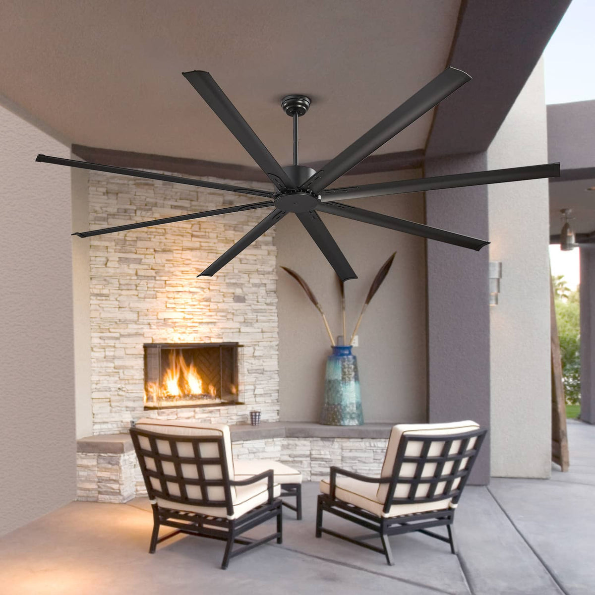 Black ceiling fan with eight blades over a patio seating area near a fireplace