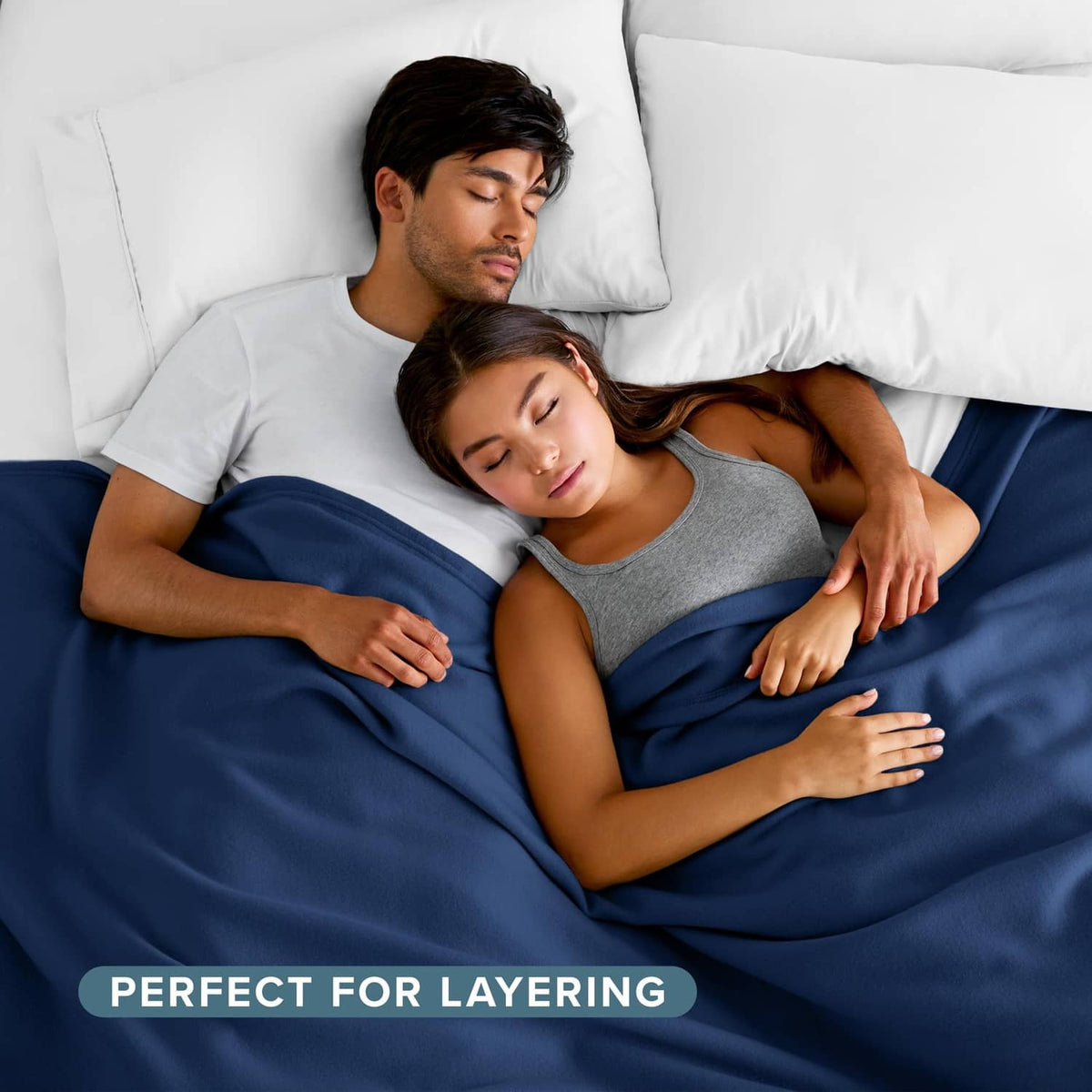 Dark blue blanket covering two people on a bed, fully draped and layered