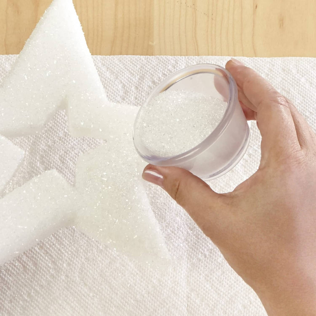 Hand holding a clear container filled with white diamond dust glitter powder