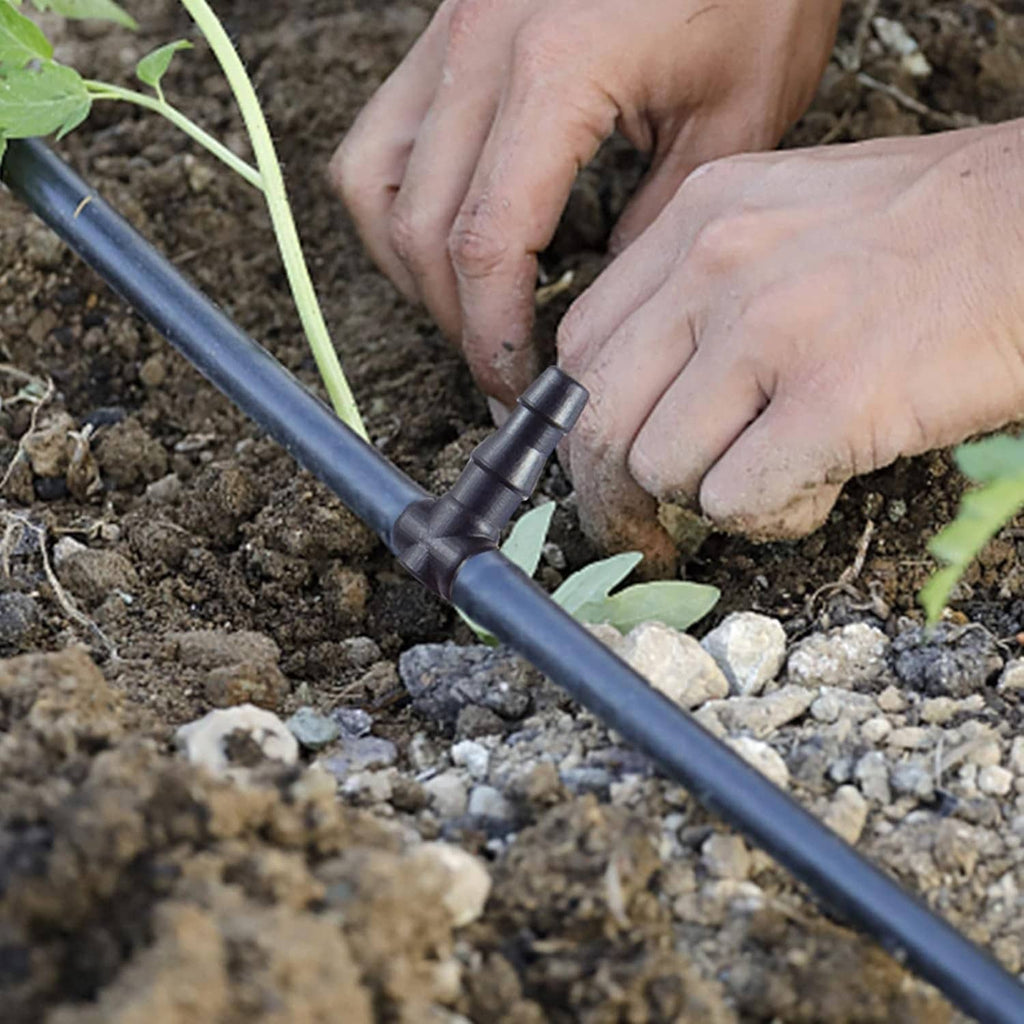 Barbed drip irrigation connector pressed onto blue tubing in outdoor soil