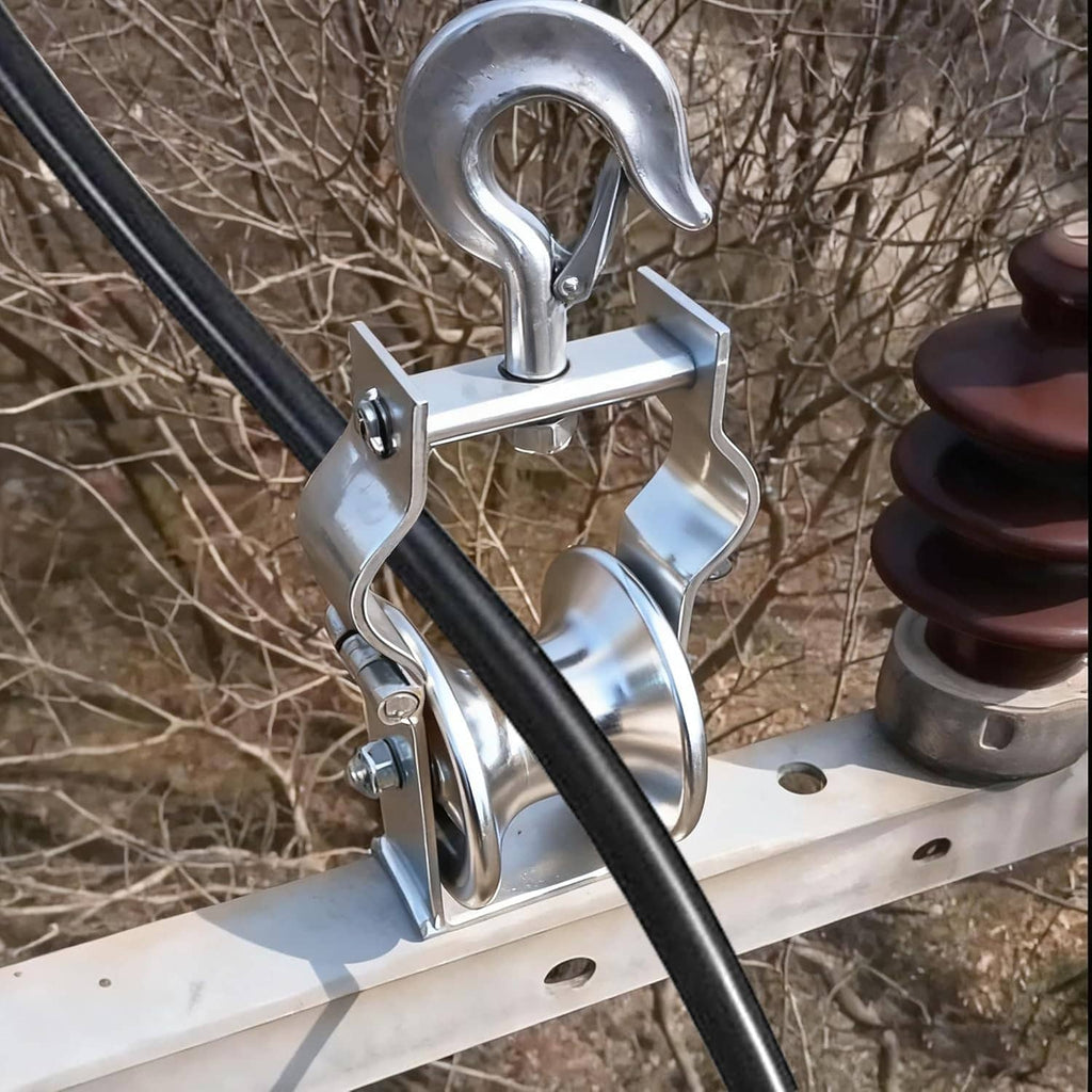 Cable pulley hook block clamped to a beam with black cable passing over the wheel