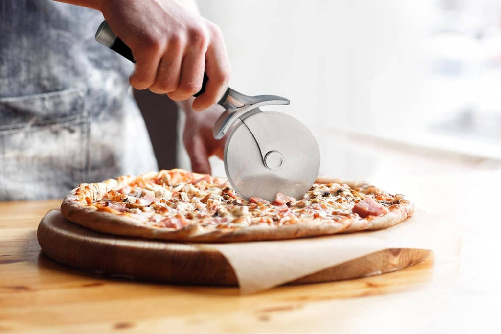 Hand using black-handled pizza wheel cutter with stainless blade on pizza