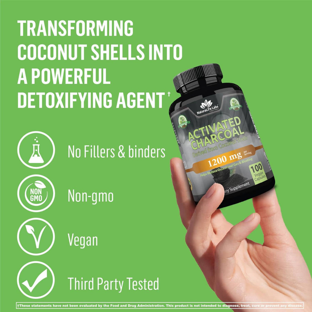 Activated charcoal capsules bottle held in hand, 1200 mg per serving