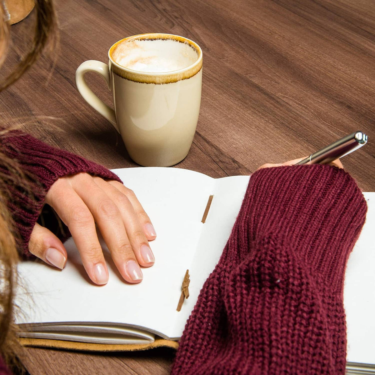 Open brown leather journal notebook with pen and writing on blank pages.