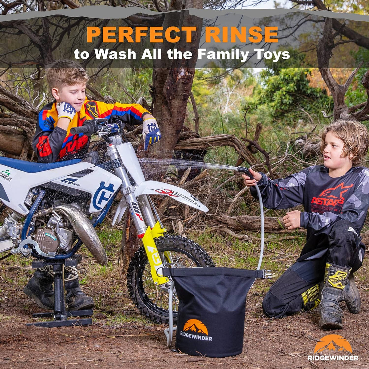 Portable camp shower dry bag with hose spraying over outdoor gear near a motorcycle