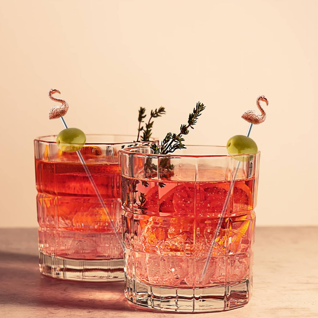 Flamingo cocktail picks with metal skewers, holding olives and herbs in glasses