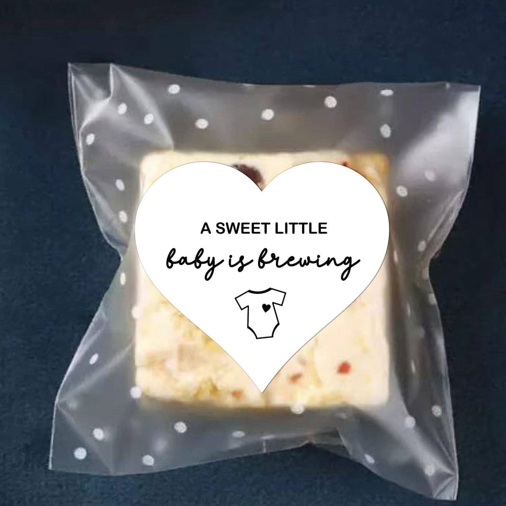 Heart-shaped sticker on a clear pouch: “A SWEET LITTLE baby is brewing” with baby icon