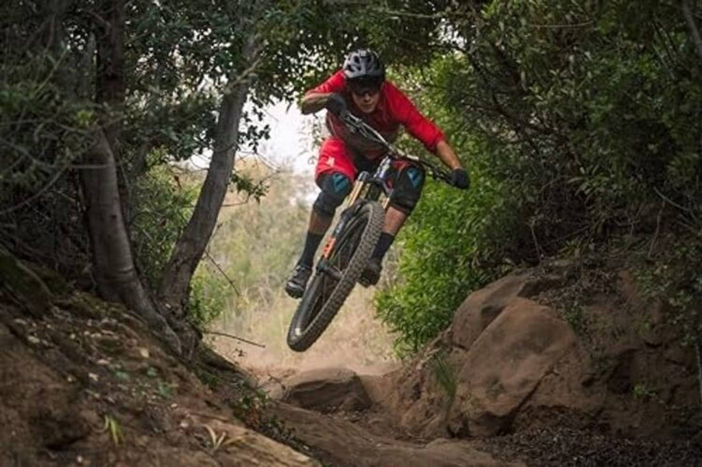 Mountain bike rider jumping a dirt trail in a wooded area