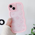 Pink clear iPhone case with repeating bow pattern and raised dual camera cutouts.
