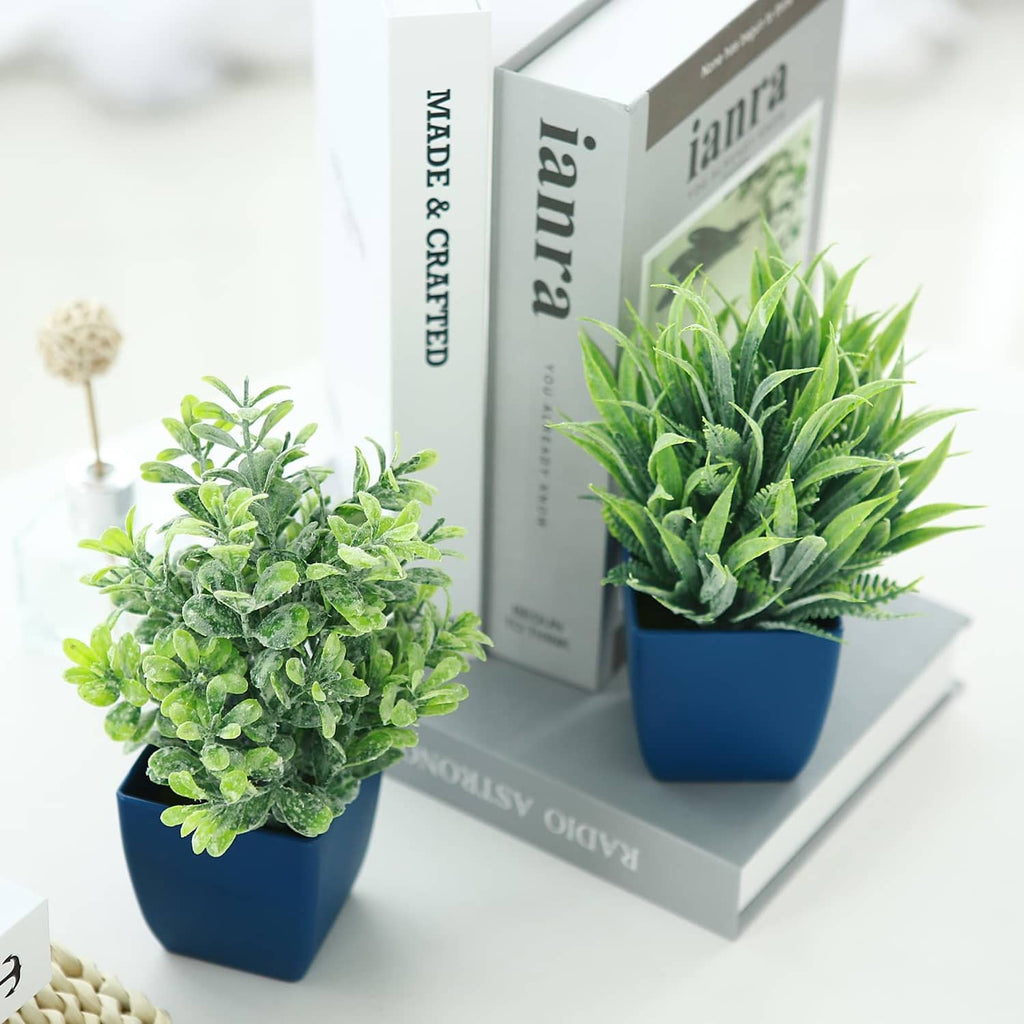 Two potted artificial plants in blue pots: green leafy bush and spiky eucalyptus