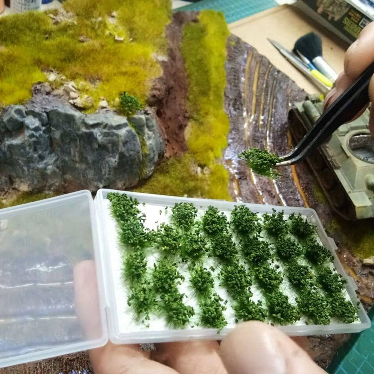 Hands holding green shrub tuft terrain strips in a clear organizer box